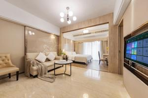 a living room with a couch and a tv at RoomMe HOTEL寓洣公寓佛山铂顿祖庙岭南天地店 in Foshan