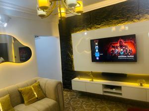a living room with a couch and a tv on a wall at Perfect Home in Lagos