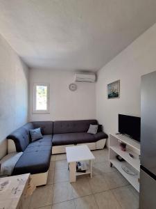 a living room with a blue couch and a tv at Robinson Agava in Selca kod Bogomolja