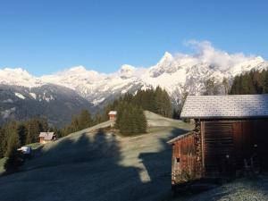 a cabin with snow covered mountains in the background at Ferienhaus Fritzensee in Bartholomäberg