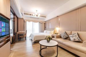 a hotel room with a couch and a bed and a tv at RoomMe HOTEL寓洣公寓佛山铂顿祖庙岭南天地店 in Foshan