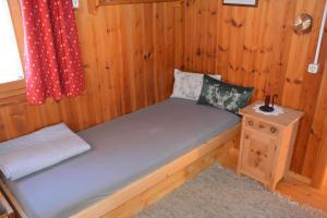 a small bed in a wooden room with a table at Ferienhaus Fritzensee in Bartholomäberg +5 photos