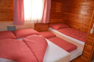a bedroom with three beds in a wooden room at Ferienhaus Fritzensee in Bartholomäberg