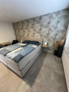 a bedroom with a bed and a concrete wall at Korantov Hram in Bukovci
