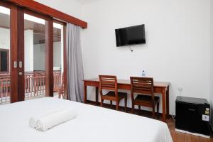 a bedroom with a bed and a desk and a television at Urbanview Hotel Arta Guna Casa in Kerobokan