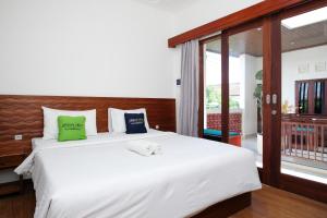 a bedroom with a large white bed and a window at Urbanview Hotel Arta Guna Casa in Kerobokan