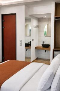 a bedroom with a bed and a bathroom with a sink at Villa Park Luxury Rooms in Paralio Astros