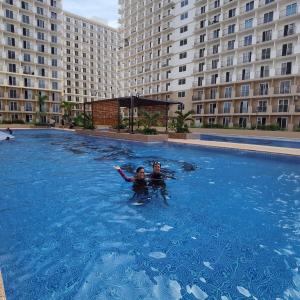 two people in a swimming pool in a large building at Affordable Condo Unit in Saekyung Phase 3 in Suba