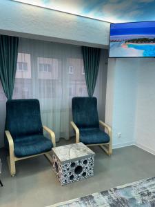 two chairs and a table in a room with a tv at Cloud Express in Petroşani
