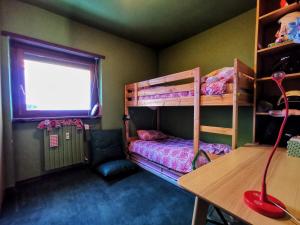 a bedroom with bunk beds and a desk and a window at Casa Verde in Sestriere