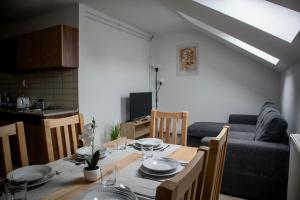 a dining room table and a kitchen with a couch at Ízisz Apartman in Mátraterenye