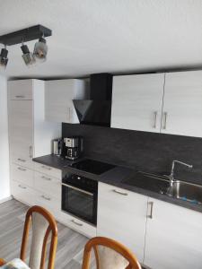 a kitchen with white cabinets and a sink at FeWo Waldblick in Goslar