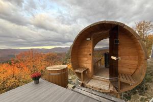 a wooden circular building with a deck and a barrel at Üveghuta Vendégház in Vágáshuta