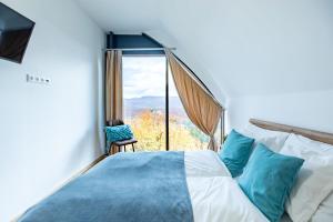 a bedroom with a bed and a large window at Üveghuta Vendégház in Vágáshuta