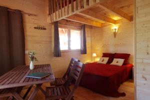 ein Schlafzimmer in einem Blockhaus mit einem Bett und einem Tisch in der Unterkunft Les Cabanes des Benauges in Arbis
