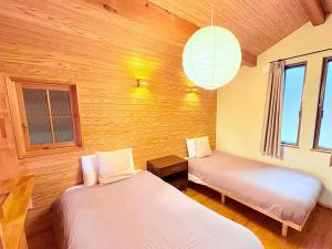 two beds in a room with wooden walls and windows at Noël HAKONE SENGOKUHARA in Moto-hakone