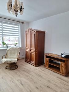 a room with a chair and a cabinet and a window at Apartament Cichy Zakątek in Ruciane-Nida +6 photos