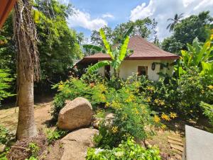 a house with a garden with flowers in front of it at Private Balinese Bungalow for 2 - Shared pool - Lamai Koh Samui in Nathon Bay