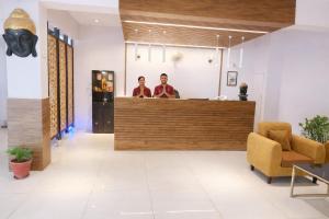 two men standing at a counter in a lobby at Hotel Stiltstay in Greater Noida