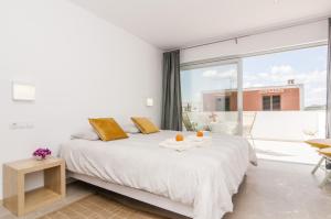 a white bedroom with a bed and a large window at Apartamento Sa Punta II in Portocolom