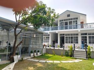 a white house with a tree in the yard at leisure valley resort in Jhājra