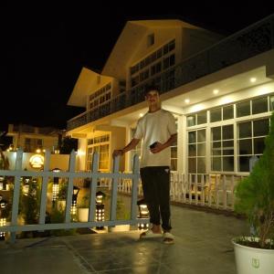 a man standing in front of a house at night at leisure valley resort in Jhājra