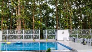 a swimming pool with a fence and trees at leisure valley resort in Jhājra