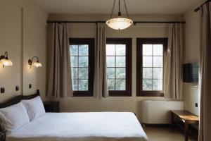 a bedroom with a white bed and two windows at Agnanti Hotel in Velventós +115 photos