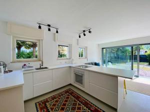 a large kitchen with white cabinets and windows at Casa Fee in Gravedona +14 photos