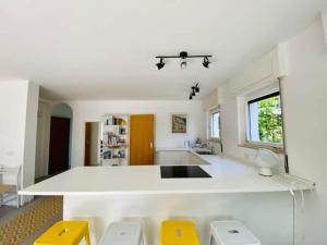 a large white kitchen with yellow stools in it at Casa Fee in Gravedona