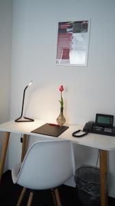 a white desk with a laptop and a vase with a flower at Amical Hotel Hagen in Hagen
