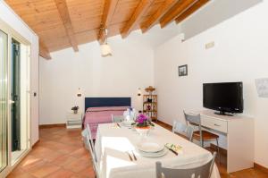 a living room with a table and a tv at Le Tartarughe Aparthotel in Letojanni