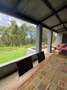 a table and chairs on a patio with a large window at Stoneygate Farm in Wakkerstroom