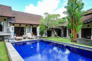 a villa with a swimming pool in front of a house at Lilis Cempaka Mas Guesthouse in Canggu