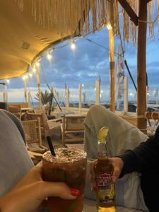 a person holding a drink and a bottle of beer at Genieten in Wenduine in De Haan