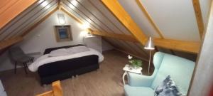 a small attic bedroom with a bed and a chair at Genieten in Wenduine in De Haan