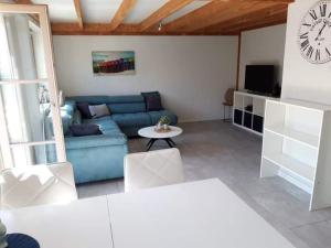 a living room with a blue couch and a clock at Genieten in Wenduine in De Haan