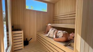 a woman is laying in a sauna at Hotel Virgilio in Riva del Garda
