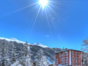ein Gebäude im Schnee mit der Sonne am Himmel in der Unterkunft arthausHOTEL in Davos