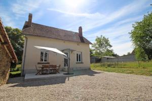 a small white house with a table and an umbrella at Le paradis de caux in Magnac-Bourg