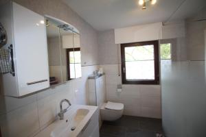 a white bathroom with a toilet and a sink at Ferienwohnung Rennsteigblick in Riechheim