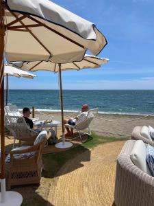 two people sitting in chairs under an umbrella on the beach at LA CALA TROCADERo in Cala del Moral