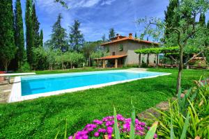 a swimming pool in a yard with a house at Villa Lo Scoiattolo by PosarelliVillas in Subbiano