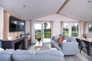 a living room with two blue couches and a tv at Willow lodge in Brynteg