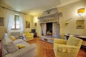 a living room with a fireplace and a couch and chairs at Villa Lo Scoiattolo by PosarelliVillas in Subbiano