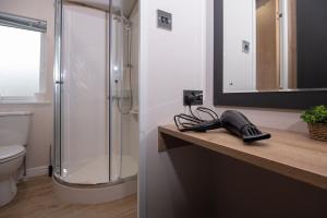 a bathroom with a shower and a phone on a counter at Willow lodge in Brynteg +42 photos
