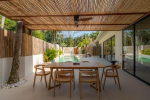 an outdoor dining room with a wooden table and chairs at K Villas Phangan 04 in Ban Madua Wan