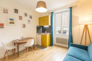 Una sala de estar con un sofá azul y una mesa. en Les Toits de Paris, en París