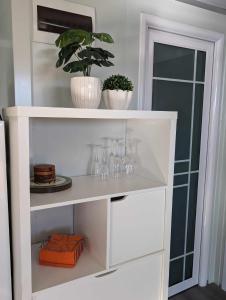 a white shelf with wine glasses and a potted plant at Timbuktoo Escape in Glen Creek +8 photos