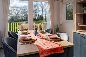 a wooden table with chairs and a tablecloth on it at Willow lodge in Brynteg